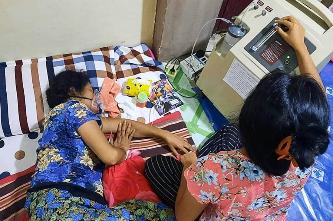 A woman with COVID-19 receives oxygen support using an oxygen concentrator provided by Community Partners International in Yangon, Myanmar.