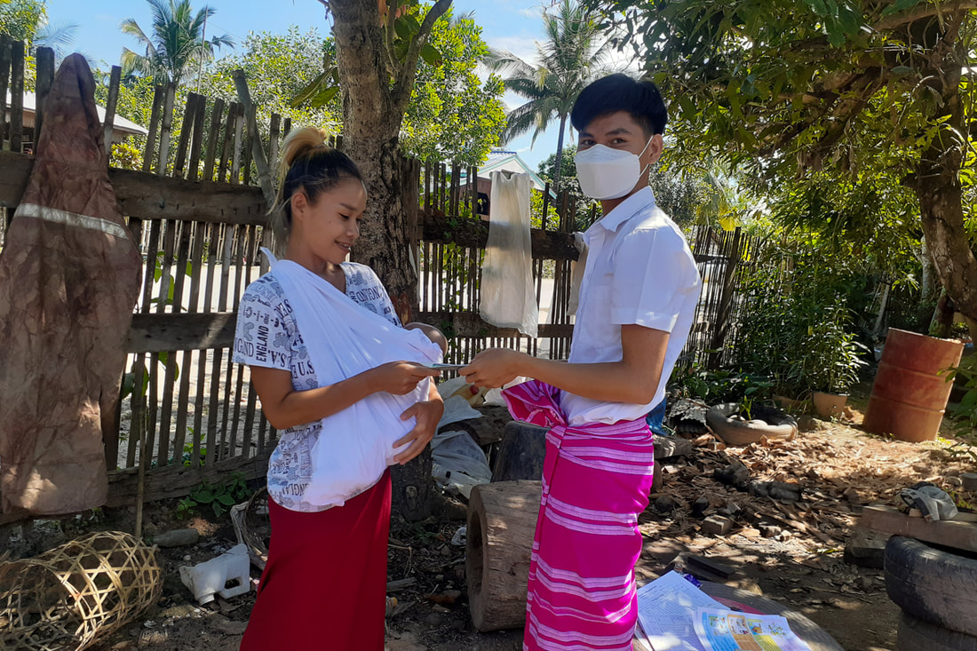 A mother and newborn in Kayin (Karen) State, Myanmar, receives a cash-for-food payment from a KEHOC representative. 