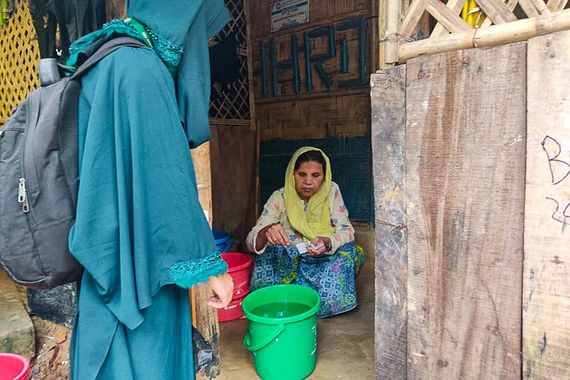 A Rohingya volunteer distributes water purification tablets during flooding in Kutupalong Refugee Camp, Bangladesh.
