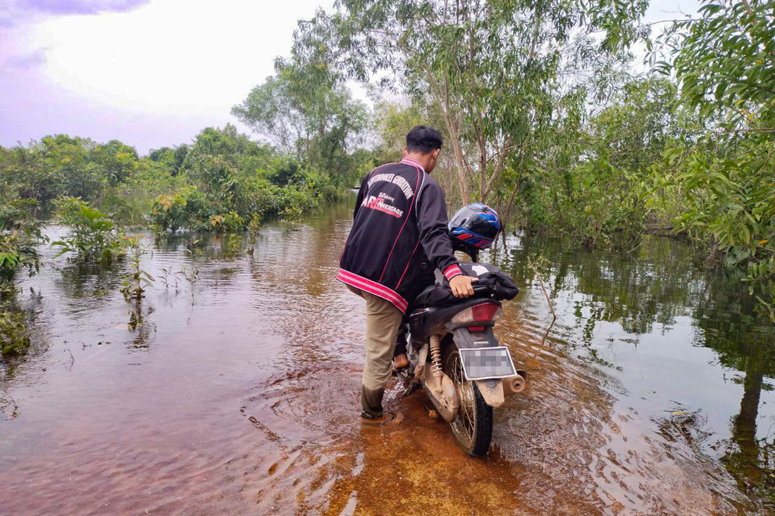 A humanitarian worker pushes a motorcycle along a road covered by floodwaters in Karen (Kayin) State, Myanmar. 