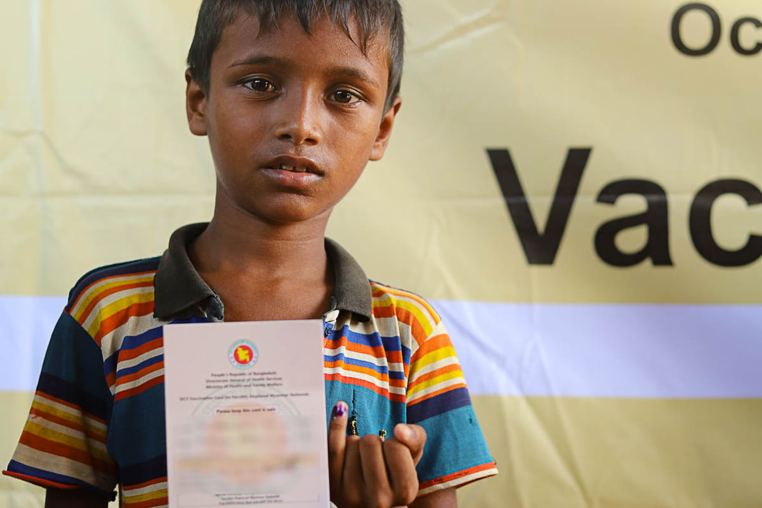 A child displays their cholera vaccination card in Kutupalong Refugee Camp, Cox's Bazar, Bangladesh.