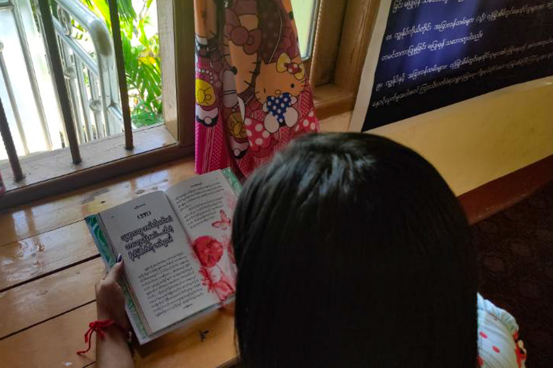 A survivor of gender-based violence reads at a TWG safe house in southeast Myanmar. 