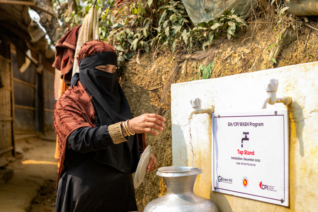 Roshida fills her water pot at the new tap stand near her shelter connected to the water network in Camp 4, Kutupalong Refugee Camp, Cox's Bazar, Bangladesh. 