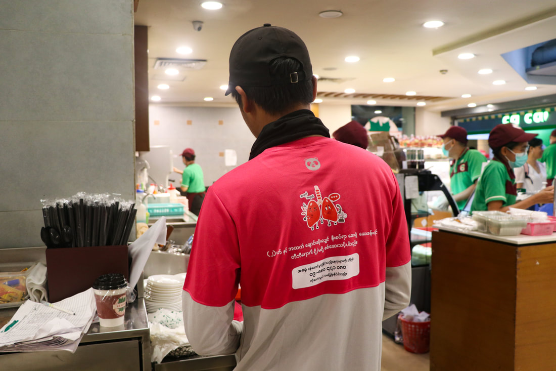 A Foodpanda rider wears a TB awareness shirt while collecting a delivery from a restaurant in Yangon, Myanmar.