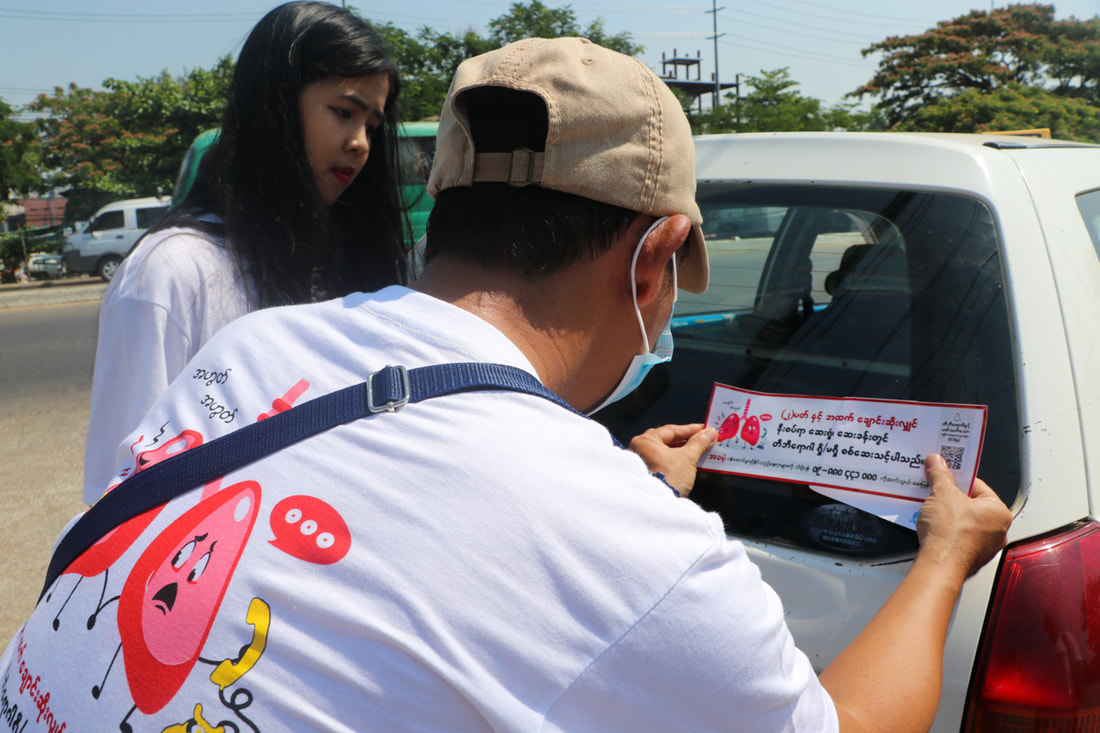 A TB awareness volunteer attaches a sticker to a taxi in Yangon, Myanmar, in March 2023.