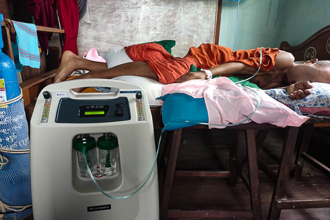 A COVID-19 patient is treated at home in Myanmar with an oxygen concentrator provided by Community Partners International.