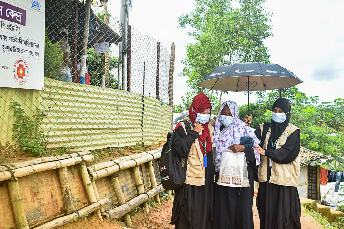 Volunteers supported by CPI help a woman to reach  a COVID-19 vaccination center in Kutupalong Refugee Camp, Bangladesh.