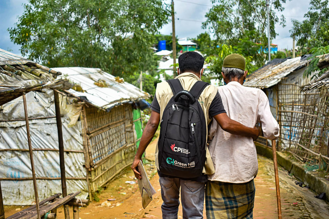 CPI-supported volunteer Osman helps Ali to reach  a COVID-19 vaccination center in Kutupalong Refugee Camp, Bangladesh.
