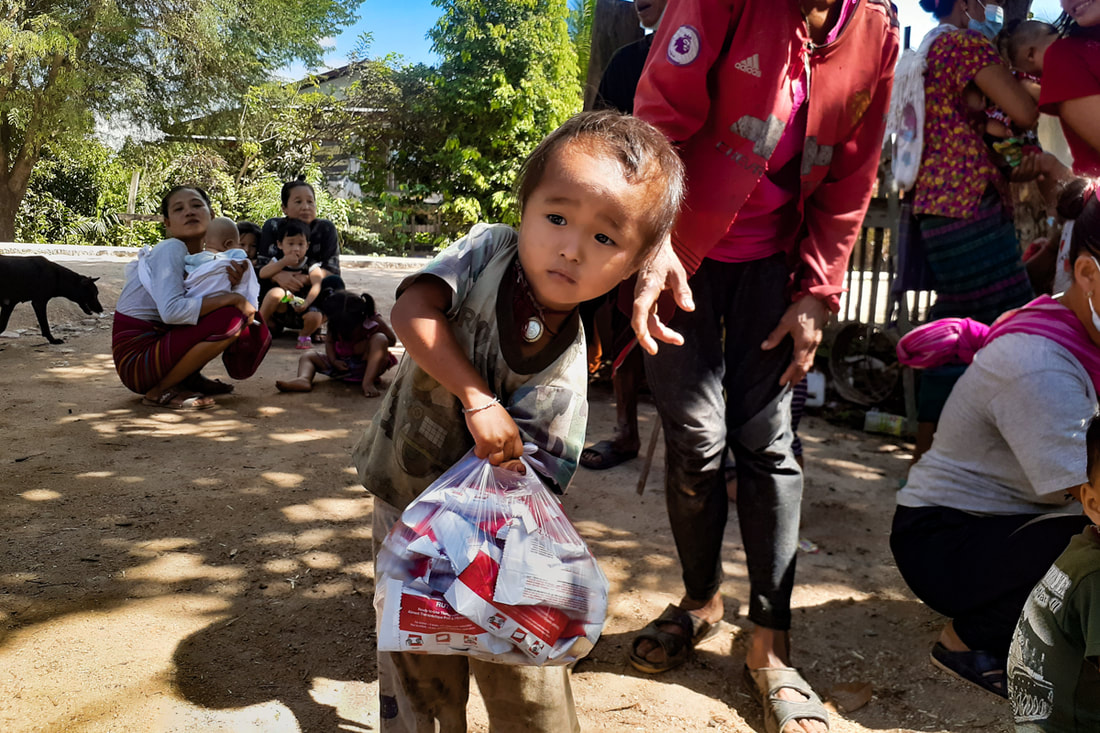 A young child carries ready-to-use therapeutic food packets in Kayin (Karen) State, Myanmar.
