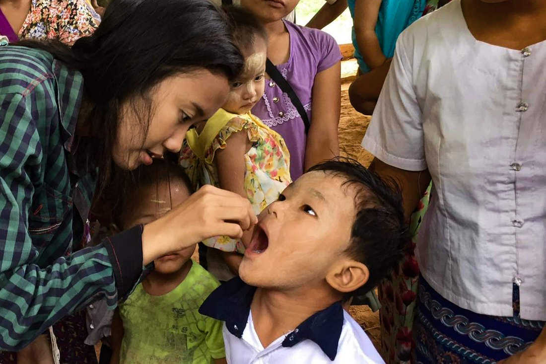 A YSDA health worker puts a Vitamin A supplement into the mouth of a child in Bago Region, Myanmar.