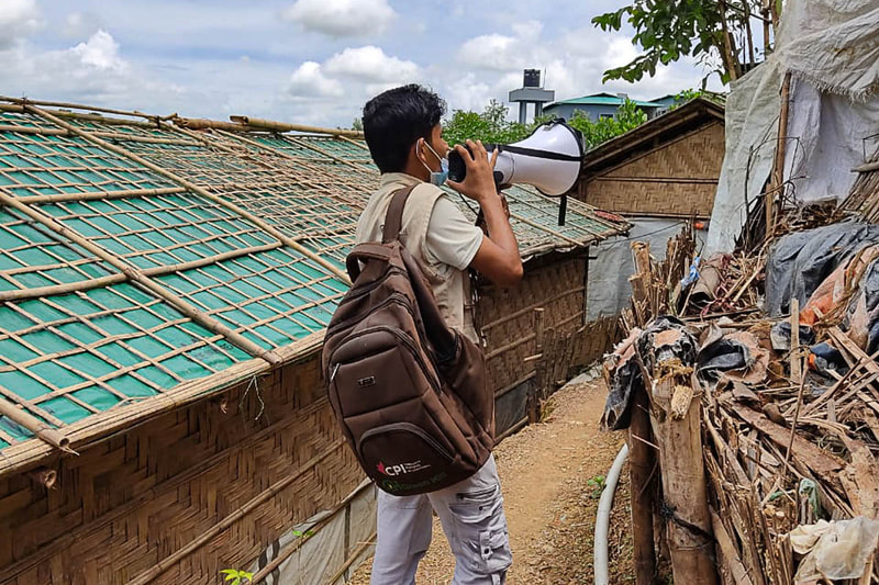 A Rohingya volunteer alerts communities to the threat of landslides during flooding in Kutupalong Refugee Camp, Bangladesh.