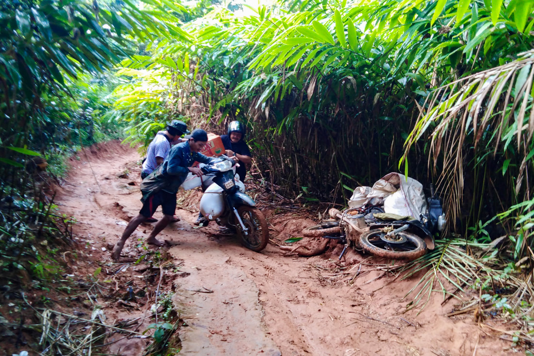 Humanitarian workers push motorcycles laden with supplies up steep and muddy tracks in Karen (Kayin) State, Myanmar. 