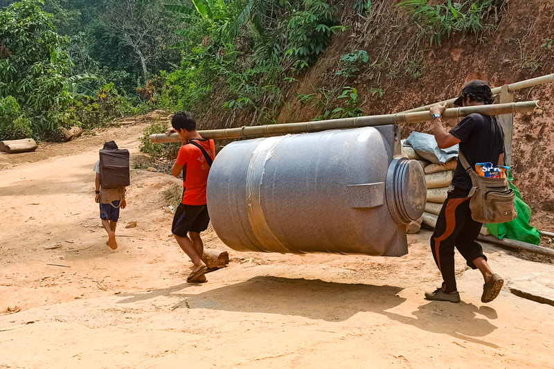Humanitarian workers carry a water tank to a community in Karen (Kayin) State, Myanmar. 