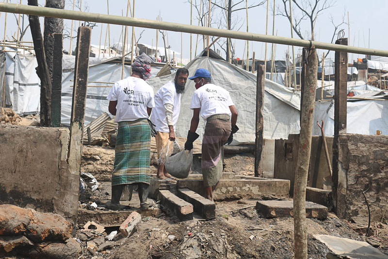 Host community and Rohingya volunteers clear fire debris in Kutupalong Refugee Camp.

