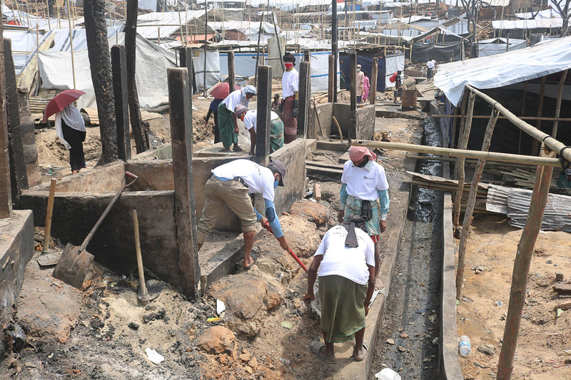 Host community and Rohingya volunteers clear fire debris in Kutupalong Refugee Camp.