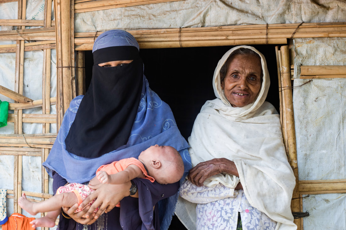 Rohingya traditional birth attendant Ruma (left) holds the baby of a mother she supported to give birth safely in Kutupalong Refugee Camp, Bangladesh. 
