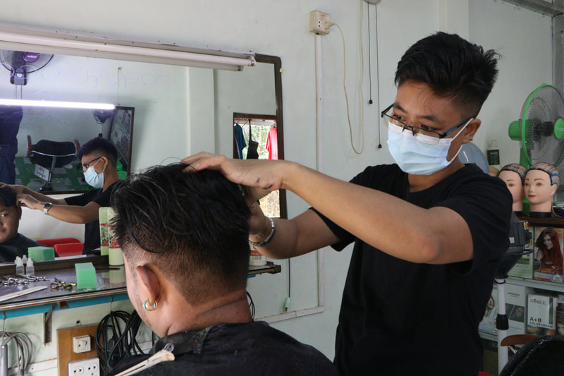 Ko Moe cuts a customer's hair at his salon in Insein Township, Yangon, Myanmar.