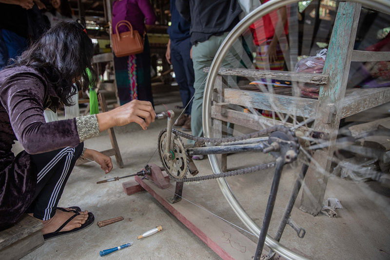 A weaver uses the spinning wheel made from a converted bicycle.