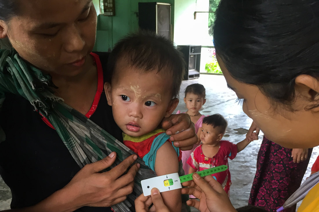 Chae's son is checked for malnutrition by a health worker using the mid-upper arm circumference measurement at a YSDA Clinic in Bago Region, Myanmar.