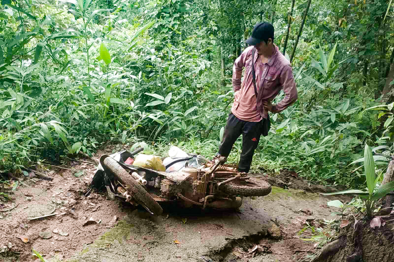 A humanitarian worker surveys an overturned motorcycle on a muddy track in Karen (Kayin) State, Myanmar. 